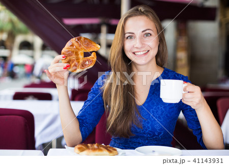 Girl is eating croissant and drinking coffee 41143931
