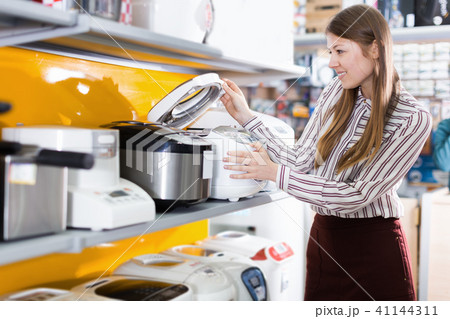 Young positive female housewife choosing multicooker 41144311