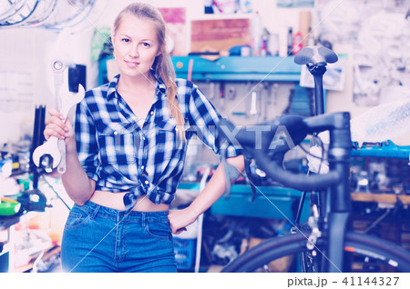 Portrait of girl who is working with instruments in workshop for bicycle. 41144327