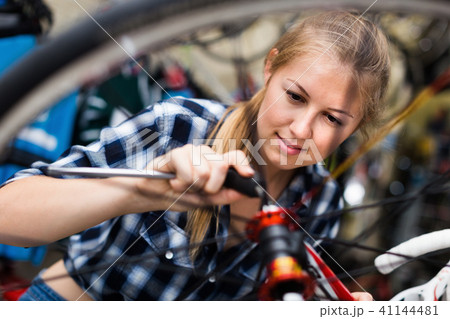 Woman is fixing wheel of bicycle in bicycle service Woman is fixing wheel of bicycle in bicycle service 41144481
