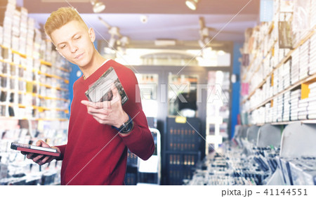 Male looking CD and DVD in shop attentively reading contents Male looking CD and DVD in shop attentively reading contents 41144551
