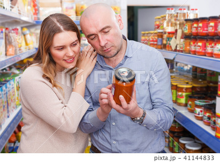 Family couple in store holding preserved jar in grocery section 41144833