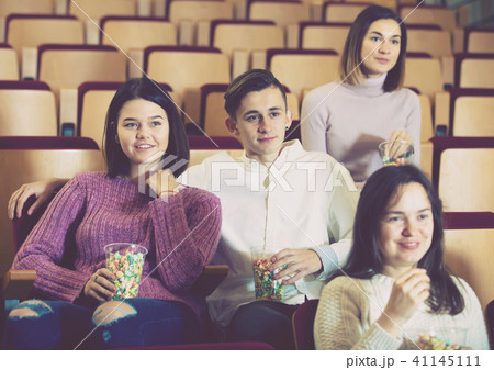 Spectators eating popcorn and watching a movie Spectators eating popcorn and watching a movie 41145111