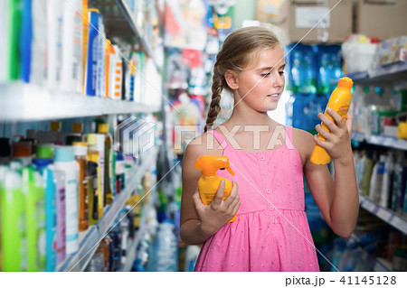 Smiling teen girl looking spray of sun protection Smiling teen girl looking spray of sun protection 41145128