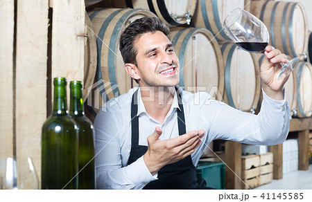 male seller holding glass on wine in cellar . 41145585