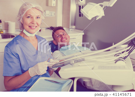 Dentist in dental clinic with patient behind 41145671