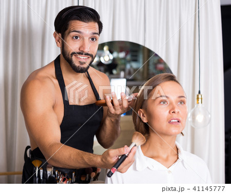 Cheerful male makeup artist applying cosmetics Cheerful male makeup artist applying cosmetics 41145777
