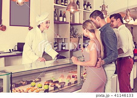 Pastry chef female is serving cakes from showcase 41146133