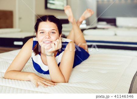 Young positive woman is lying on bed and posing playfully in the store Young positive woman is lying on bed and posing playfully in the store 41146346