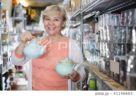 Smiling woman choosing kettle for drinking tea Smiling woman choosing kettle for drinking tea 41146663