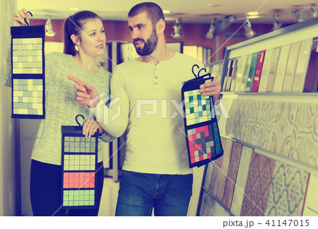 Laughing couple looking sample of ceramic tile Laughing couple looking sample of ceramic tile 41147015