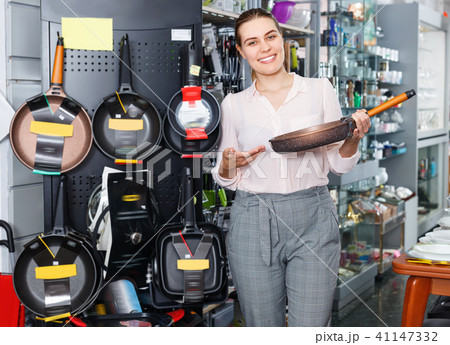 Young female buyer choosing new pan for kitchen in the dishes store 41147332