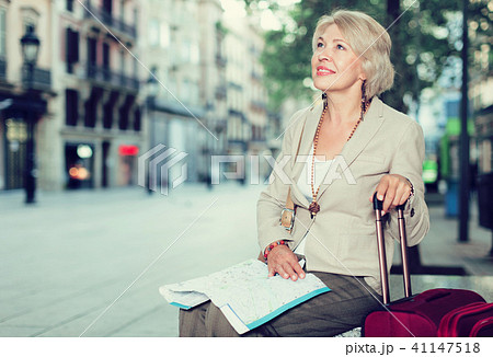 Elegant adult tourist woman is sitting with map in time walking Elegant adult tourist woman is sitting with map in time walking 41147518