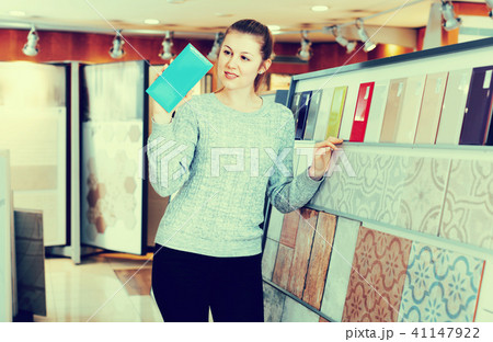 Portrait of female looking sample of ceramic tile in shop 41147922