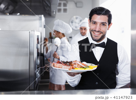 Waiter with seafood dish in kitchen of restaurant 41147923