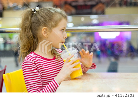 Girl child drinking juice in cafe Girl child drinking juice in cafe 41152303