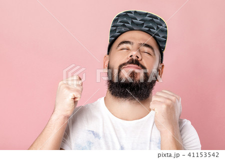 Young cheerful bearded football fan in cap celebrating 41153542