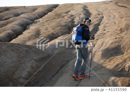 Image from back of growth of female tourist with backpack and sticks for walking on mountain 41155590