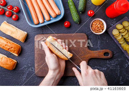 Photo on top of table with ingredients for hot dogs, cutting board, man's hands Photo on top of table with ingredients for hot dogs, cutting board, man's hands 41163603