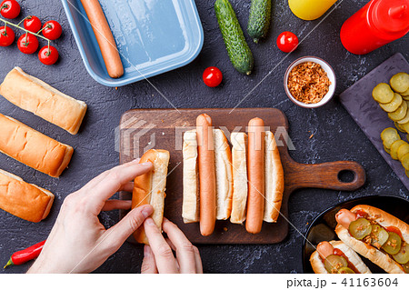 Image from above of man doing hotdogs on cutting board on table with sausages Image from above of man doing hotdogs on cutting board on table with sausages 41163604