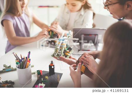 Cheerful teacher and kids working with helicopter Cheerful teacher and kids working with helicopter 41169131