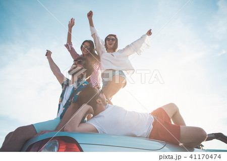 Excited young men and women having fun on vehicle outdoor  41170474