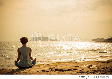 ヨガ 海 ピラティス 女性 夕方 海辺 リラックスの写真素材