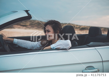 Happy young woman is driving a convertible car  41170753