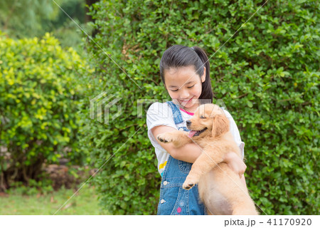 girl holding a little golden retriever dog in park 41170920