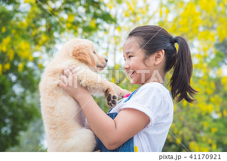 girl holding a little golden retriever dog in park 41170921