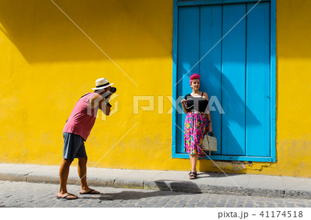 Man taking a photo of a girl against a yellow wall Man taking a photo of a girl against a yellow wall 41174518