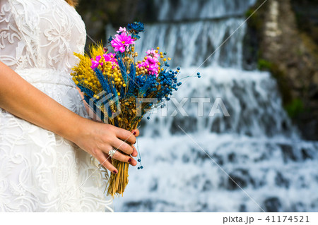 Bride holding wedding bouquet in front of a waterfall 41174521