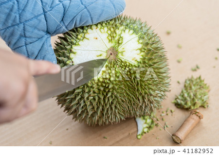 Hand using knife to peel durian. 41182952