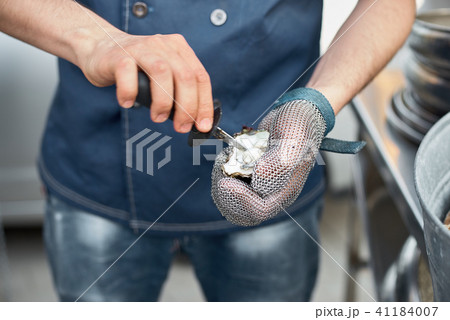 Fresh oyster held open with a oyster knife Fresh oyster held open with a oyster knife 41184007