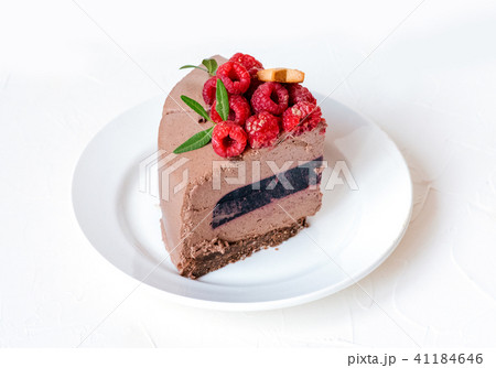Chocolate uncountable slice of cake on plate, with raspberries on white background, With green 41184646