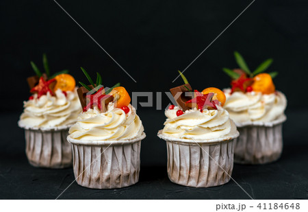 Four puff pastries with cream, chocolate cakes with biscuits. Close-up on a black background. In a 41184648