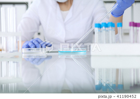 Close-up of professional female scientist in protective eyeglasses making experiment with reagents Close-up of professional female scientist in protective eyeglasses making experiment with reagents 41190452