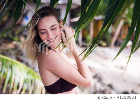 A beautiful young woman with long blonde hair posing on a beach dressed in sexy bikini top. She 41190931