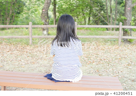 ベンチに後向きに座る女の子の写真素材