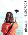 Woman standing taking a photo selfie on the sea 41207006
