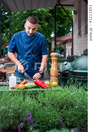 beautiful European-looking chef standing at restaurant terrace, slicing vegetables and looking at 41211951