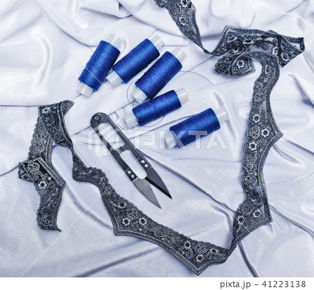Scissors and blue thread on fabric background. 41223138