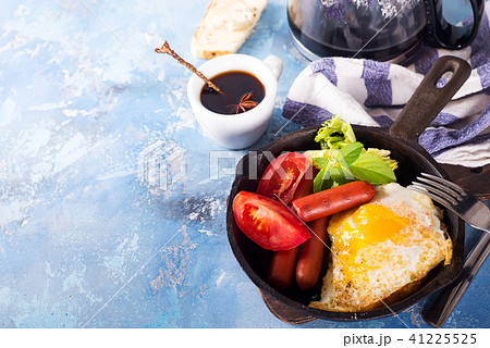 Homemade delicious breakfast on a pan with fried egg, toast, sausage, vegetable, black coffee Homemade delicious breakfast on a pan with fried egg, toast, sausage, vegetable, black coffee 41225525