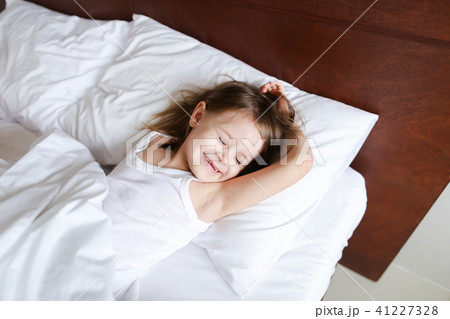 Little caucasian girl sleeping in morning before school on bed with white linens. Little caucasian girl sleeping in morning before school on bed with white linens. 41227328