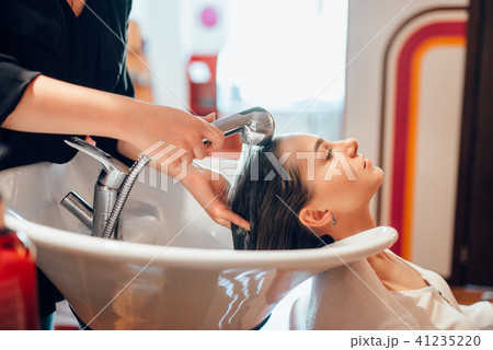 Hairdresser washes customer hair in basin Hairdresser washes customer hair in basin 41235220