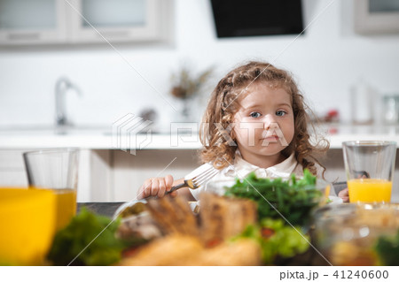 Cute curly girl having lunch in kitchen Cute curly girl having lunch in kitchen 41240600