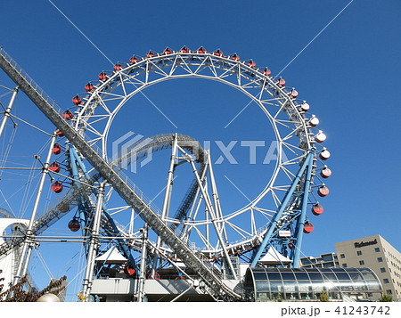 東京ドームシティアトラクションズのセンターレス観覧車をくぐり抜けるジェットコースターの写真素材