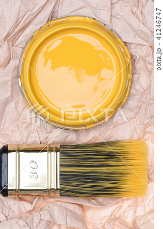 Paintbrush and can lid  with yellow paint, closeup 41246747