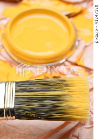 Paintbrush and can lid  with yellow paint, closeup 41247120