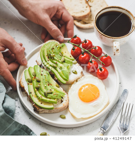 Toast with avocado, fried egg, tomatoes and cup of coffee. Healthy breakfast 41249147